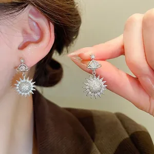 Elegant silver saturn and sun drop earrings with sparkling cubic zirconia on a model