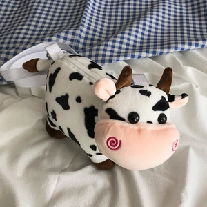 Detail of cute plush cow crossbody bag featuring soft black and white cow print fabric