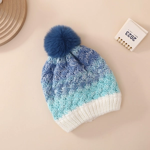 Detail of kids knit hat showing gradient waves from dark blue to white with faux fur pom