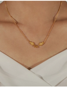 Close-up of golden double fish pendant necklace with small beads worn on the neck