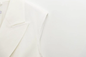 Detailed close-up of white sleeveless blazer dress featuring premium textured fabric