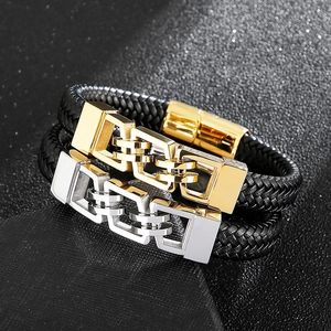 Detail of interlocking gold and silver metal buckles on black braided leather bracelets