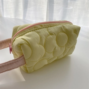 Close-up of a yellow quilted makeup bag with pink zipper and soft bubble texture
