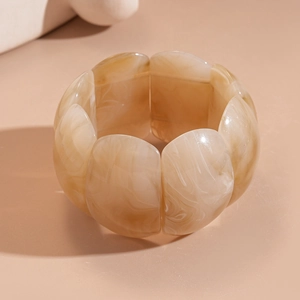 Detail of chunky acrylic bracelet with beige and light brown marble texture and glossy finish