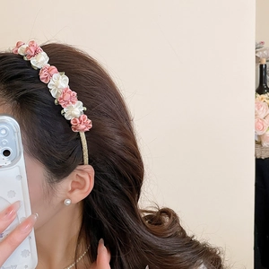 Detail view of handmade pink and white silk roses on a shimmering gold floral headband