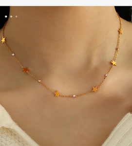 Close-up of gold star necklace with crystal accents worn on the collarbone