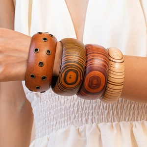 Macro detail of stacked wooden and leather bangles with metal rivets on model's wrist