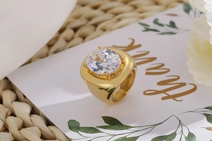 Close-up of gold plated ring featuring a large oval clear zircon in a four-prong setting