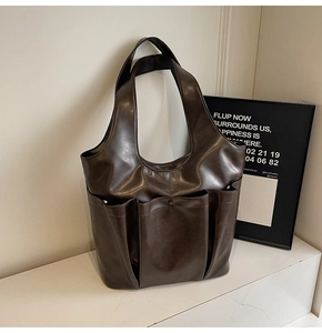 Detail of dark brown faux leather tote bag with three functional outer pockets