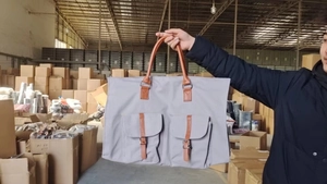 Sac à vêtements en toile grise avec poignées en cuir marron et deux poches avant