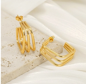 Close-up of triple-layered geometric gold cube earrings on a premium stone pedestal