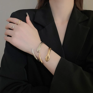 Detailed view of gold and silver snake-shaped cuff bracelet and wrap ring set