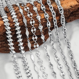 Selection of stainless steel chains with various link designs on silk and wood background