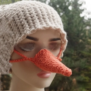 Detail of handmade orange carrot knit nose warmer with tie straps for winter warmth
