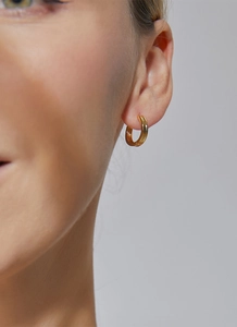 Close-up of elegant gold hoop earring worn by a model showcasing polished metal texture