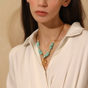 Detail of 18K gold-plated paperclip necklace with turquoise stone and coral sea star charm
