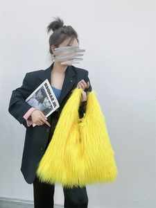 Detail showing high-capacity yellow long faux fur tote bag styled with casual outfit