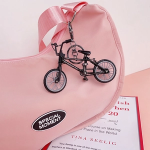 Detailed view of a black metal mountain bike keychain hanging on a stylish pink bag