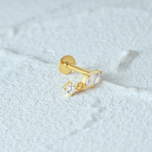 Macro detail of 925 silver moon stud earring with gold plating and clear gemstones