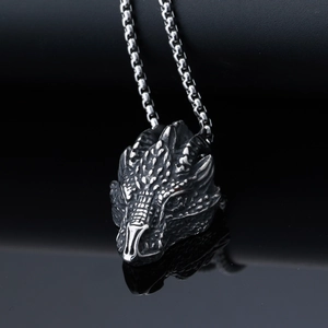 Macro shot of silver dragon head pendant with detailed scales on black mirror background