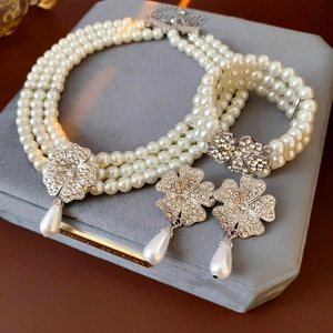 Detail of luxury pearl jewelry set with crystal flower charms on gray velvet display pad
