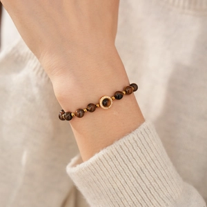 Bracelet en perles d'oeil de tigre avec touches dorées et pendentif zircon au poignet
