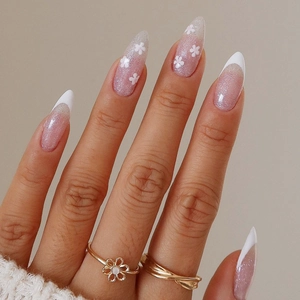 Detailed close-up of almond-shaped press-on nails with white flower and French tips