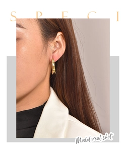 Close-up of model wearing irregular gold-plated earrings with a smooth polished finish