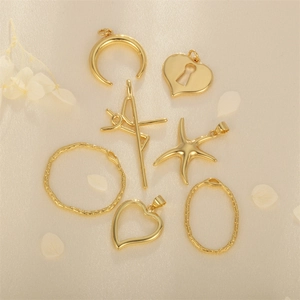 Assorted gold-plated charms including heart, starfish, and moon shapes on silk background