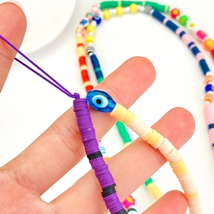 Macro detail of multi-colored flat bead phone strap featuring a blue evil eye bead
