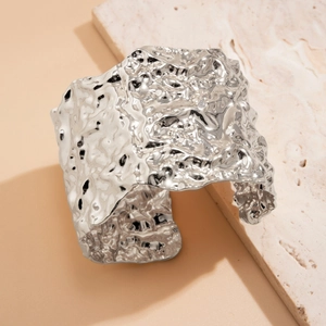 Punk style wide open silver bangle with irregular hammered texture on stone background