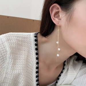 Elegant gold long fringe earrings with three pearls on a model in a natural setting