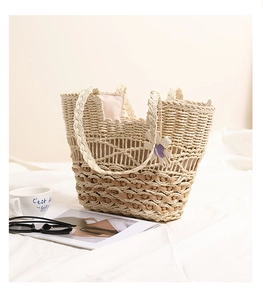 Detailed macro of a beige hollow straw bag with purple flower charm on white fabric