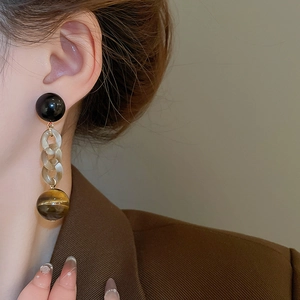 Detail view of vintage dangling earrings with tiger eye stone texture and amber resin links