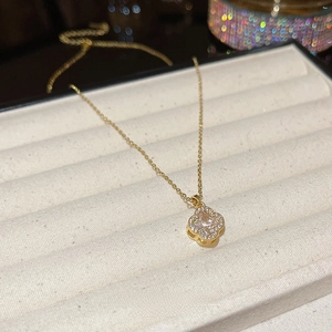 Macro view of gold clover pendant with sparkling zircon inlays on a jewelry display tray