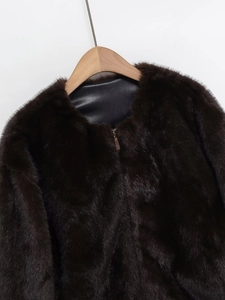Detail of faux fur bomber jacket featuring dark brown texture and golden metal zipper