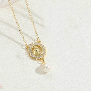 Detailed macro view of gold plated Virgin Mary pendant with white zircon and pearl drop