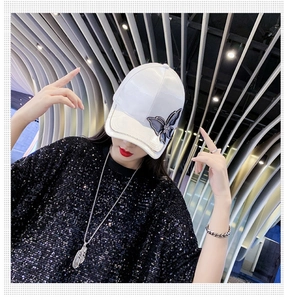 Detail of white satin baseball cap with butterfly rhinestone accent on model