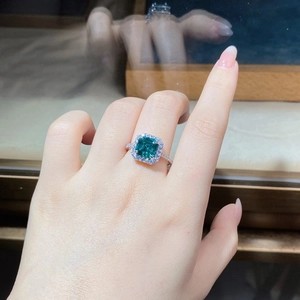 Close-up of S925 silver emerald cut green stone ring with pavé diamonds on finger