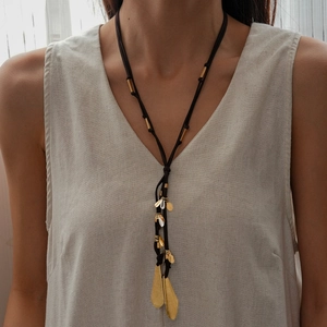Détail du collier à pendentif goutte vintage avec feuilles dorées sur cordon