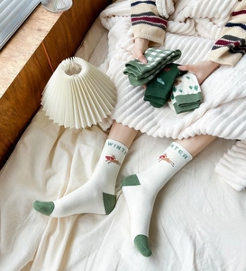 Close-up of festive green plaid and elk embroidery patterns on thick cotton Christmas socks