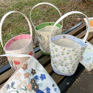 Floral print canvas bucket bags with diverse flower patterns on a park bench