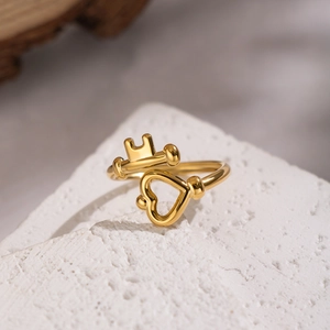 Detailed view of an 18K gold crown heart ring on a minimalist stone background