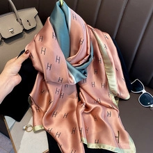 Close-up of pink and green silk wool scarf with letter H pattern and soft texture