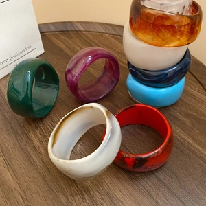 Close-up of colorful irregular resin bangles with marble texture on dark wood table