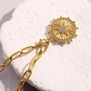 Detail of 18K gold plated stainless steel necklace with starburst coin pendant on stone