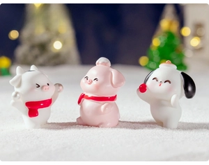 Miniature resin farm animals including cow pig and dog wearing red winter scarves on snow