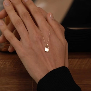 Gold minimalist padlock necklace worn on hand with polished surface and fine chain