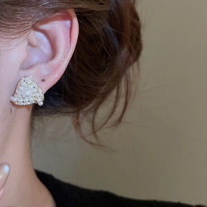 Macro shot of triangle pearl earring with cubic zirconia studs on a female ear
