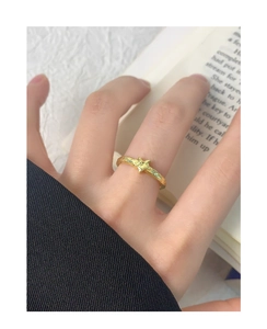 Macro shot of a gold star ring with hammered texture on a model finger for detail